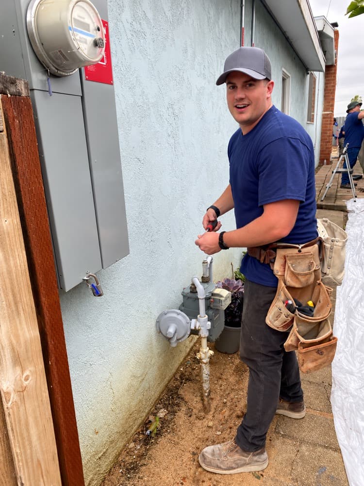 Crew member working at a gas meter beside a house